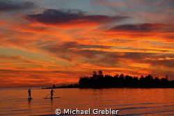 A couple share a quiet evening on stand-up paddle boards ... by Michael Grebler 